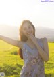 A woman standing in a field with her arms outstretched.