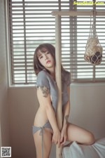 A woman sitting on top of a bed next to a window.