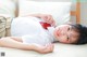 A young girl laying on a bed with a red bow tie.