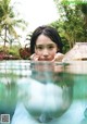 A young girl in a white dress is submerged in a pool.