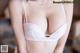 A woman wearing a white bra and panties on a bed.
