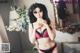 A woman in a red and black lingerie posing in front of a mirror.