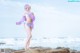 A woman in a bikini standing on a rock by the ocean.